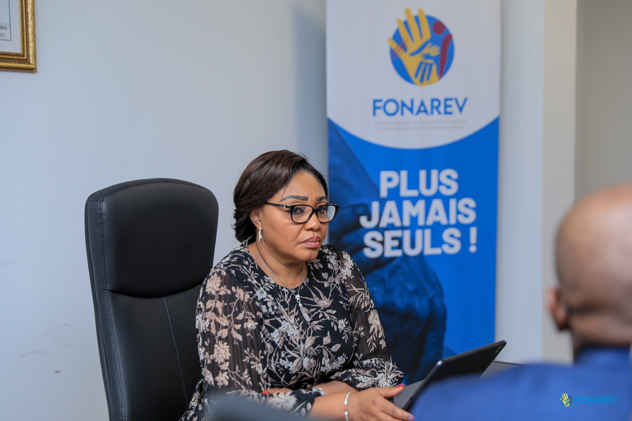 Denise Nyakeru Tshisekedi seated in front of a FONAREV banner bearing the slogan "Never alone again!"